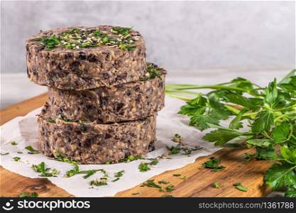 Raw veggie burger with black beans on wood countertop