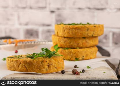 Raw veggie burger with chickpeas, vegetables and parsley leaves on kitchen countertop.