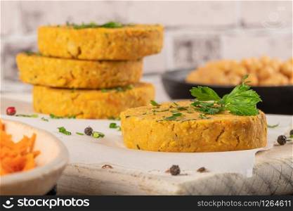Raw veggie burger with chickpeas, vegetables and parsley leaves on kitchen countertop.