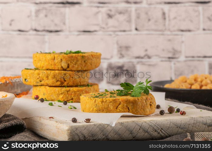 Raw veggie burger with chickpeas, vegetables and parsley leaves on kitchen countertop.