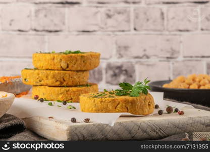 Raw veggie burger with chickpeas, vegetables and parsley leaves on kitchen countertop.