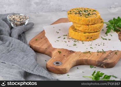 Raw veggie burger with chickpeas, vegetables and parsley leaves on kitchen countertop.