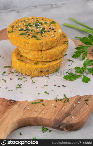 Raw veggie burger with chickpeas, vegetables and parsley leaves on kitchen countertop.