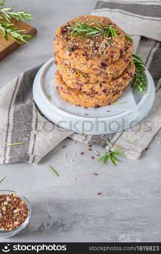 Raw veggie burger with quinoa, red beens, vegetables and rosemary leaves on kitchen countertop