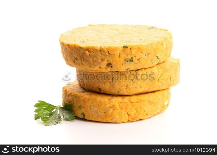 Raw veggie burgers with chickpeas and vegetables with parsley leaves on white background.