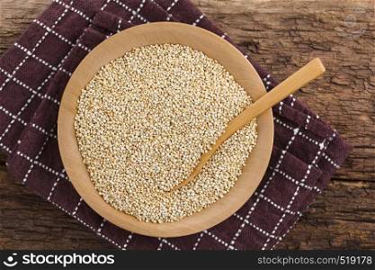 Raw white quinoa seeds (lat. Chenopodium quinoa) on wooden plate with wooden spoon, photographed overhead (Selective Focus, Focus on the quinoa). Raw White Quinoa Seeds
