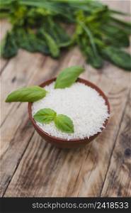 raw white rice bowl with fresh basil leaves weathered wooden plank