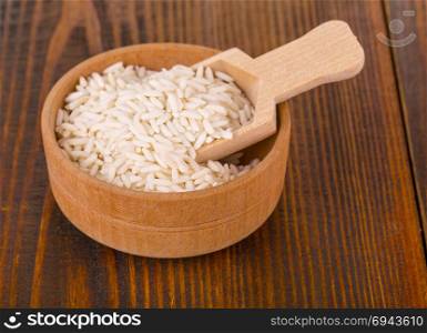 raw white rice in a Cup with wooden spoon on a wooden table