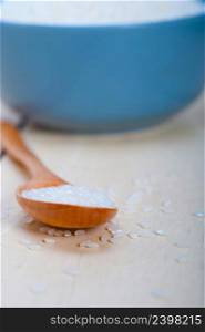 raw white rice on wood spoon and blue bowl extreme close up 