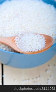 raw white rice on wood spoon and blue bowl extreme close up