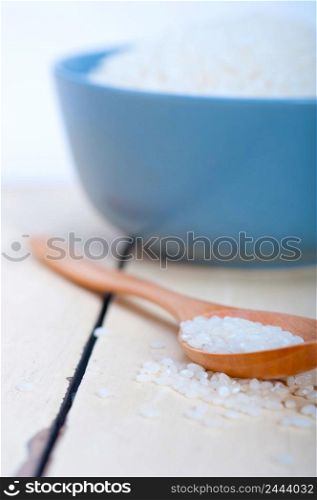 raw white rice on wood spoon and blue bowl extreme close up