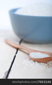 raw white rice on wood spoon and blue bowl extreme close up