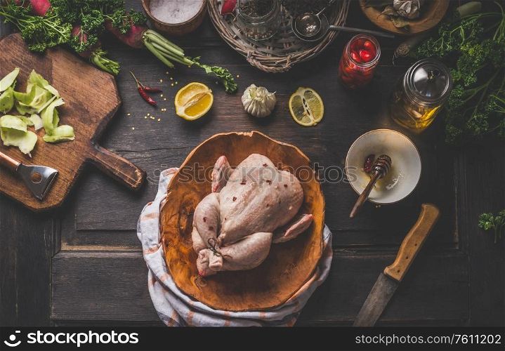 Raw whole chicken on dark rustic background with ingredients for tasty home cooking. Preparation and chicken marinating with lemon, honey and mustard. Home cuisine. Top view