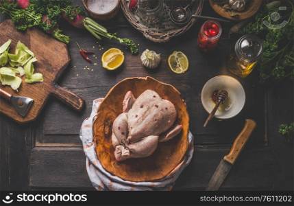 Raw whole chicken on dark rustic background with ingredients for tasty home cooking. Preparation and chicken marinating with lemon, honey and mustard. Home cuisine. Top view