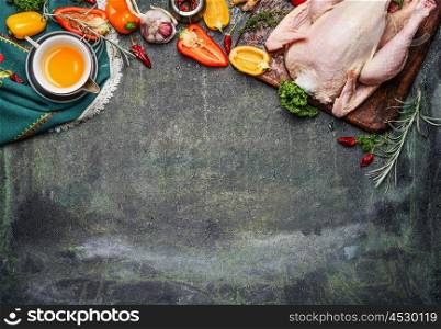 Raw whole chicken with oil and vegetables ingredients for tasty cooking on rustic background, top view, border. Healthy food or diet eating concept.