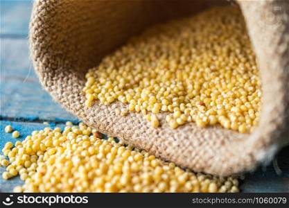 Raw yellow millet is scattered on the blue boards near the bag. Close-up.. Raw yellow millet is scattered on the blue boards near the bag.