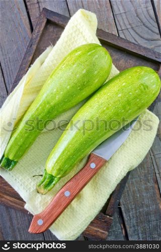 raw zucchini on wooden tray and on a table