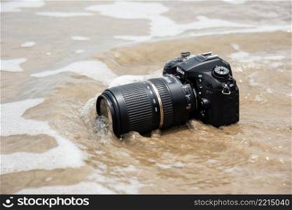 Rayong, Thailand - May 27, 2017 : Unidentified photographer demo waterproof DSLR camera with telephoto lens on beach it wet from water sea wave when travel and test using in the extreme environment. DSLR camera on beach wet from water sea wave