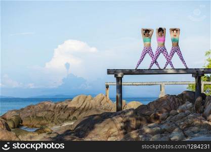 RAYONG THAILAND - MAY2,2018 : three asian woman playing yoga on sea pier,yoga is popular trend for healthy lifestyle people in thailand