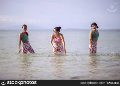 RAYONG THAILAND - MAY2,2018 : three asian woman wearing yoga suit standing in sea water and laughing with happiness emotion