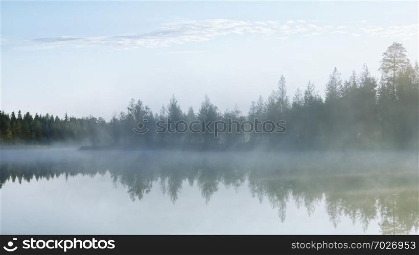 Rays of morning light fall on the mirror surface of a forest northern lake through the trees and white dense fog - atmospheric natural landscape. Selective focus, blurred filter.