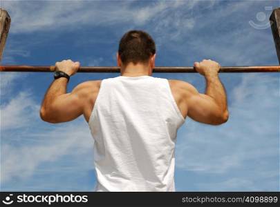 Reaching Goal: Strong Man Doing Pull-ups on a Bar in a Park