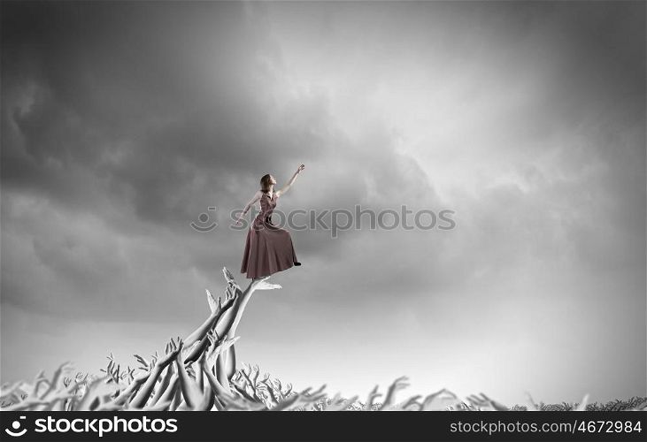 Reaching out. Young woman in evening dress walking on hands of crowd of people