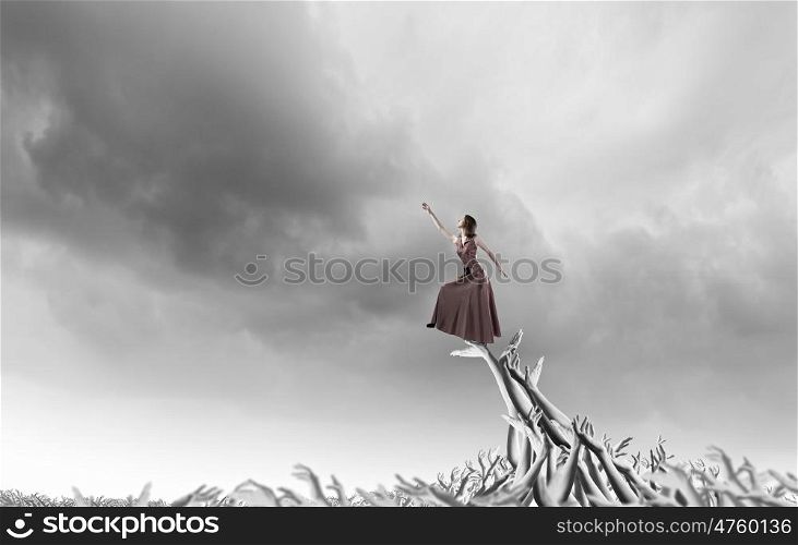 Reaching out. Young woman in evening dress walking on hands of crowd of people