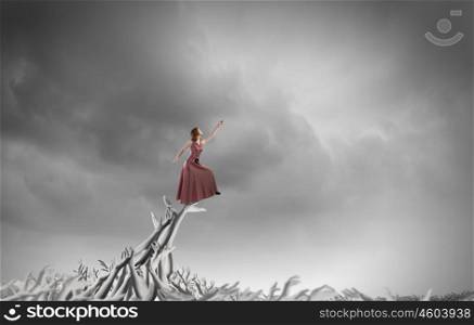Reaching the top. Young woman in evening dress walking on hands of crowd of people