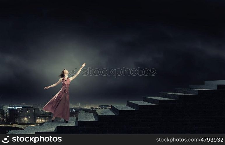 Reaching the top. Young woman in evening long dress walking up the staircase