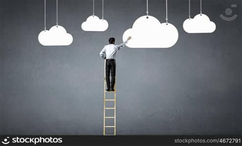 Reaching top. Businessman climbing ladder to top and touching cloud