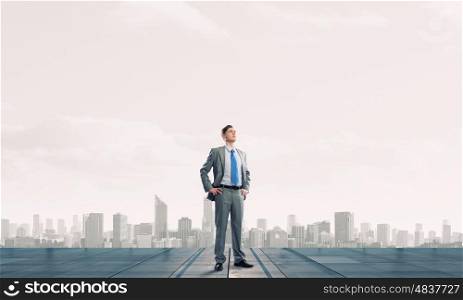 Reaching top of success. Young confident businessman standing on top of building