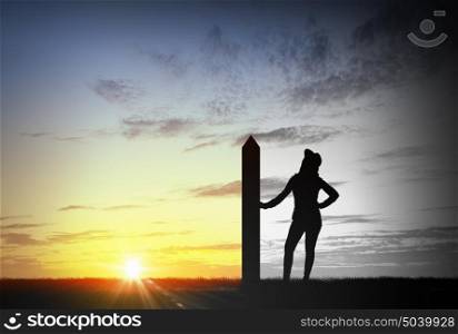 Reaching top of world. Silhouette of young woman with arrow banner on mountain top