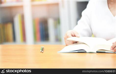 read a book library / Girl student open open book on the table with bookshelf background , selective focus copy space