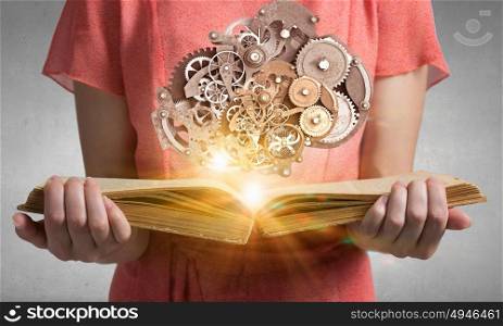 Read to broaden your mind. Close view of woman holding book and gear mechanism on pages