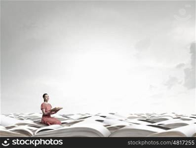 Read to broaden your mind. Young attractive woman sitting in pile and reading book