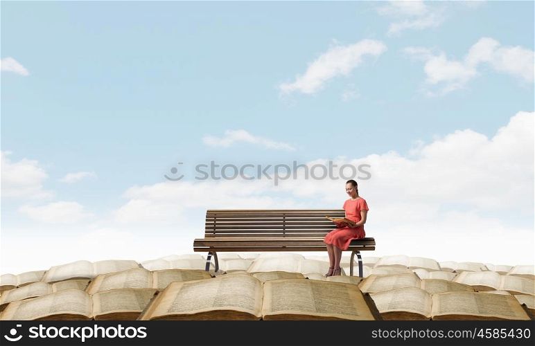 Read to broaden your mind. Young attractive woman sitting on bench and reading book