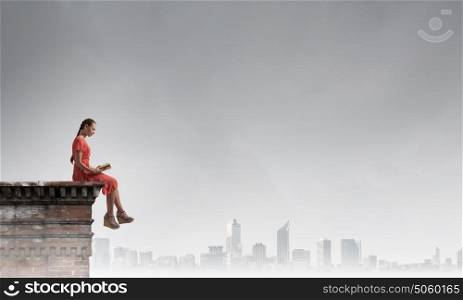 Read to broaden your mind. Young attractive woman sitting on top of building and reading book