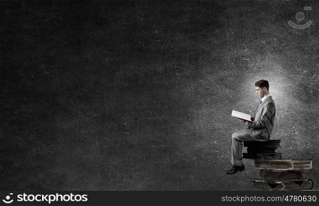 Read to broaden your mind. Young businessman sitting in pile of old books