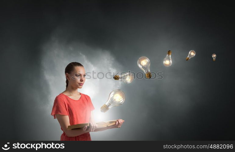 Read to broaden your mind. Young woman holding book with light bulb on pages