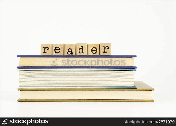 reader word on wood stamps stack on books, library and education concept