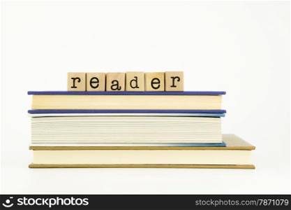 reader word on wood stamps stack on books, library and education concept