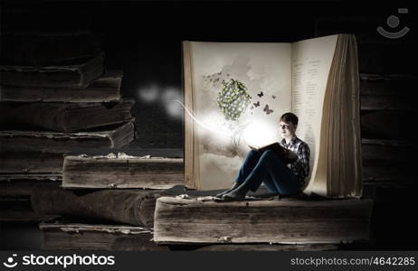 Reading and imagination. Teenager boy in jeans and shirt reading book