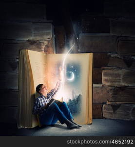 Reading and imagination. Teenager boy in jeans and shirt reading book