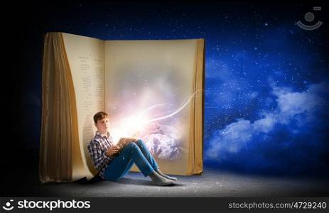 Reading and imagination. Teenager boy in jeans and shirt reading book