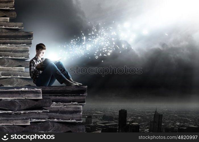 Reading and imagination. Teenager boy in jeans and shirt reading book