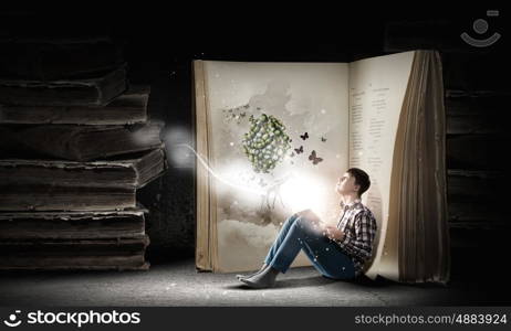 Reading and imagination. Teenager boy in jeans and shirt reading book