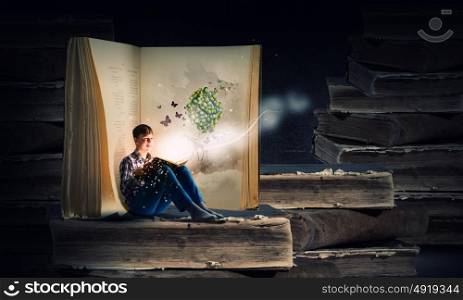 Reading and imagination. Teenager boy in jeans and shirt reading book