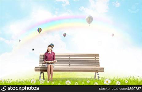 Reading and imagination. Young woman sitting on bench and reading book