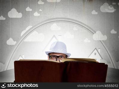 Reading book. Young man in glasses with opened book in hands